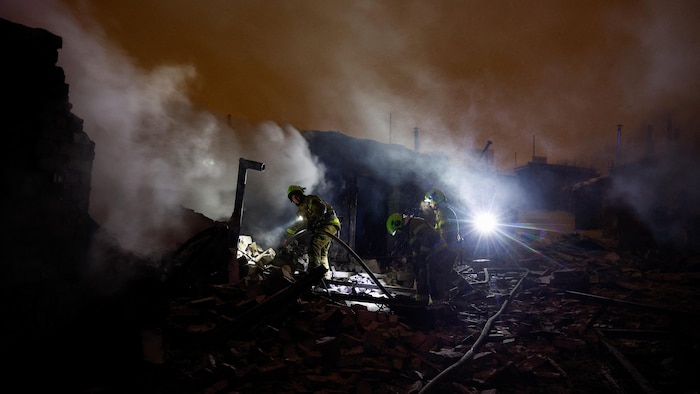 Des pompiers interviennent dans un complexe de garages automobiles endommagés lors d'une attaque russe à Kiev, en Ukraine, le 9 janvier 2026. 