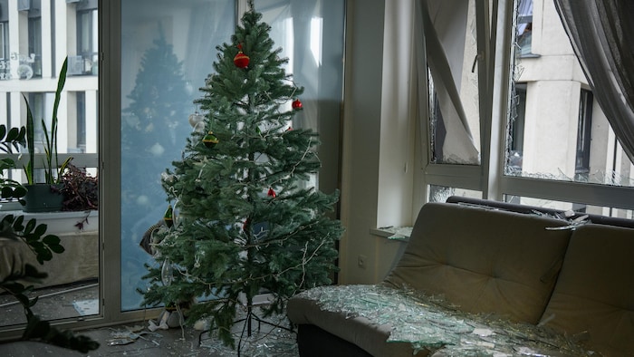 La vitre cassée d'une fenêtre est éparpillée sur le divan, le plancher et autour d'un sapin de Noël, à Kiev.