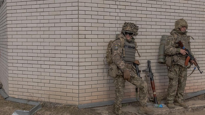 Des soldats s'accotent le long d'un mur.