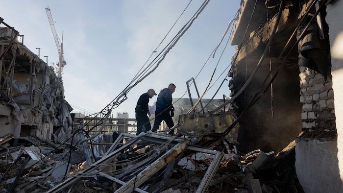 Des résidents marchent dans les décombres d'une maison, détruite dans une frappe russe, à Kiev, le 2 juin 2026.