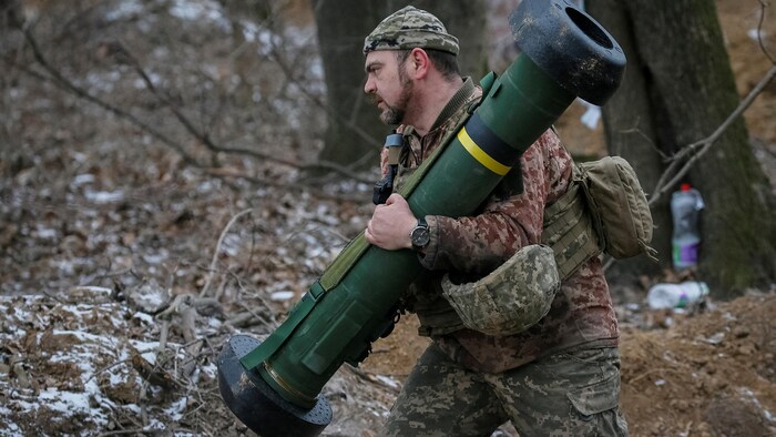 Un soldat tient un missile entre ses mains.