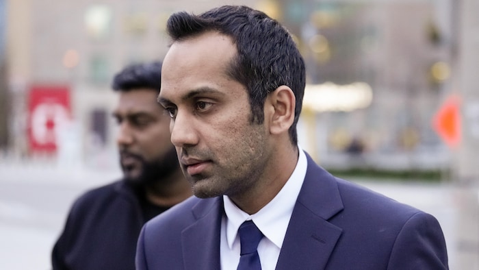 Umar Zameer, portant un veston, quitte le palais de justice.