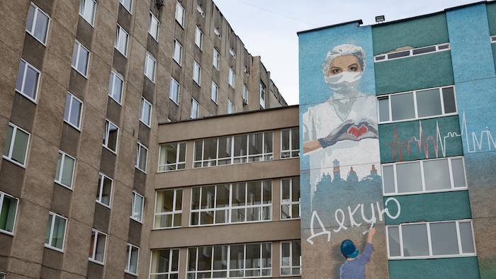 Un bâtiment affiche une murale représentant un travailleur de la santé. 