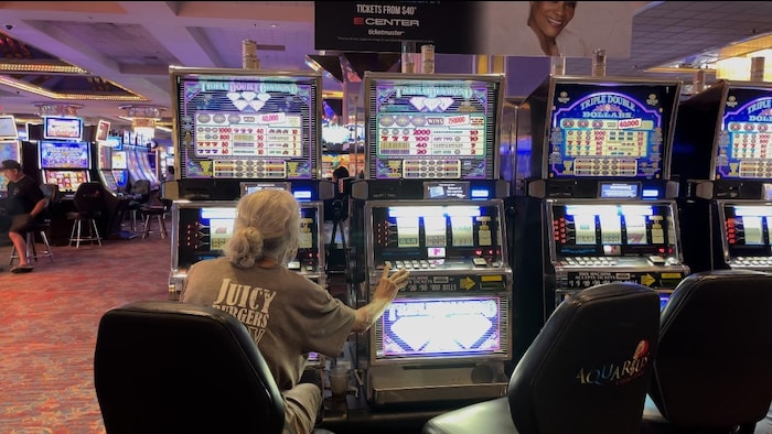 Une femme joue sur deux machines au Casino.