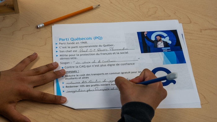 Une élève écrit les priorités du PQ sur une feuille.