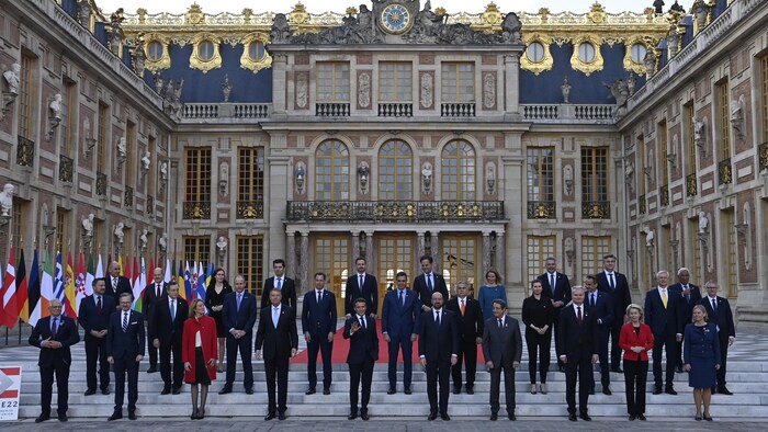 Des chefs d'État sont debout devant le château de Versailles, en France.