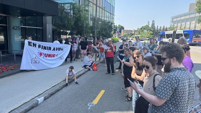 Des dizaines de personnes se regroupent devant une bannière où on peut lire en finir avec punir.