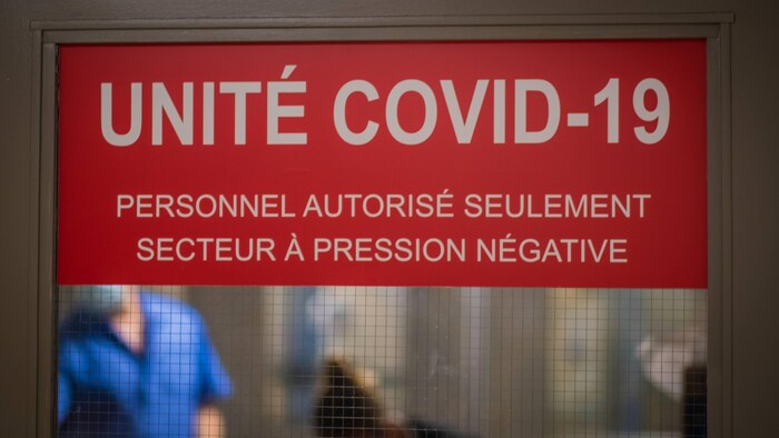 Une affiche Unité COVID-19 sur les portes-battantes dans un hôpital. 