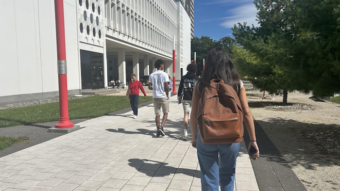 Une étudiante, sac sur le dos, marche vers un pavillon d'étude.