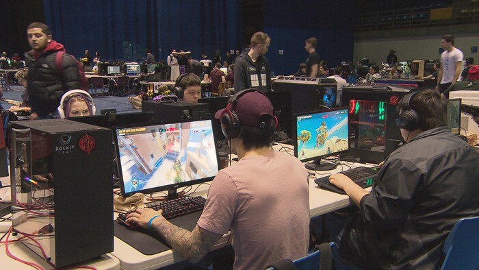 Des centaines de jeunes dans une salle jouent à des jeux vidéo sur leur ordinateur respectif.