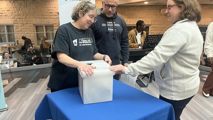 Trois personnes ferment une capsule le 03-03-2026.