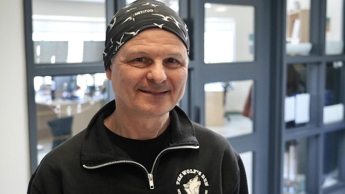 Un homme debout sourit à la caméra.