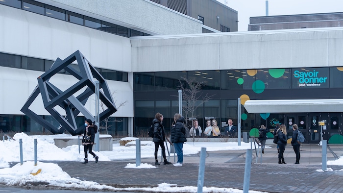 La structure des cubes à l'Université du Québec à Trois-Rivières en hiver avec des étudiants, dont une qu'on voit avec un masque.
