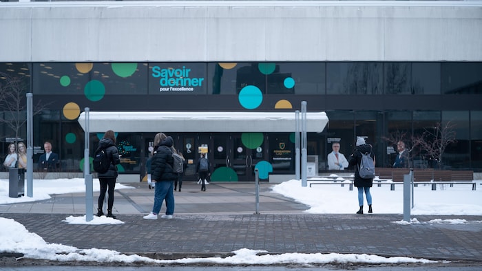 Des étudiants sont dehors devant l'entrée principale de l'Université du Québec à Trois-Rivières.