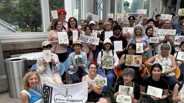 Un groupe de personnes montrant leurs dessins à la caméra.