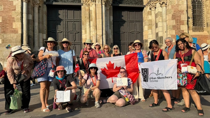 Un groupe de personne posent derrière un drapeau canadien.