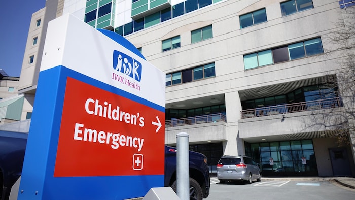 Une enseigne à l'extérieur dans le stationnement qui pointe vers le bâtiment et indique qu'il s'agit de l'entrée de l'urgence de l'hôpital pour enfants.