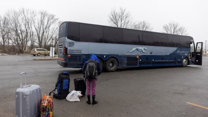 A young person waits with their families' belongings after getting off a bus and waiting for a taxi to cross into Canada at Roxham Road, an unofficial crossing point from New York State to Quebec, in Plattsburgh, New York, U.S. March 25, 2023. (Carlos Osorio/REUTERS)