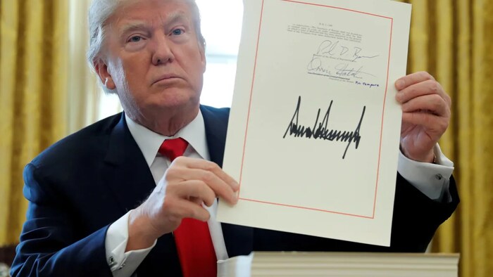 Trump got a popularity bounce after he signed a major tax bill in 2017, seen here. It was temporary. Could the same happen with Biden?