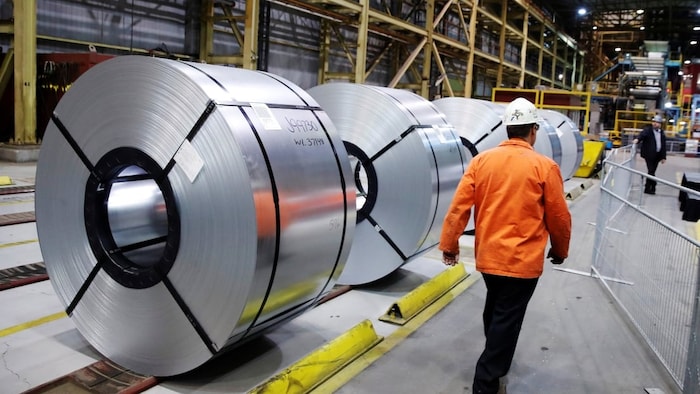 Un ouvrier passe devant des rouleaux d'acier à l'usine ArcelorMittal Dofasco de Hamilton, le 13 mars 2018. 