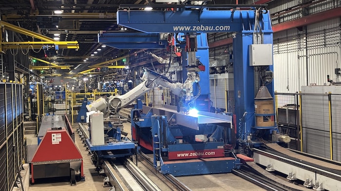 Un énorme robot fait de la soudure dans une usine de l'entreprise Canam.