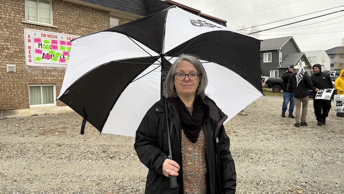 Julie Bolduc regarde vers l'avant avec un parapluie.
