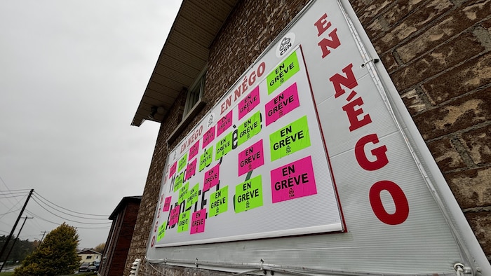 Une pancarte avec le slogan «en négo» qui se répète à divers endroits et avec plusieurs autocollants indiquant «en grève».