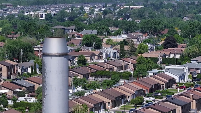Une cheminée à l'avant-plan d'une vue aérienne d'un quartier résidentiel.