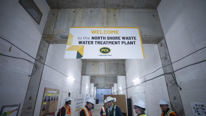 Des hommes en tenues de chantier dans l'usine de traitement des eaux en construction à North Vancouver en Colombie-Britannique.