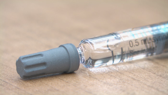 Un gros plan sur une aiguille d'un vaccin sur une table.