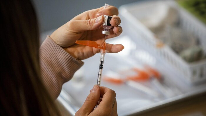Une infirmière remplit une seringue de vaccin.