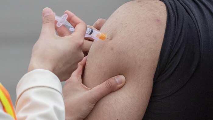 Une personne se fait injecter le vaccin dans l'épaule.