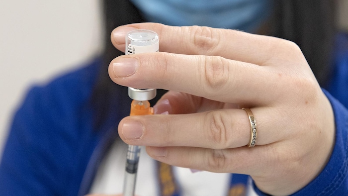 Une infirmière verse du vaccin de la fiole à la seringue.
