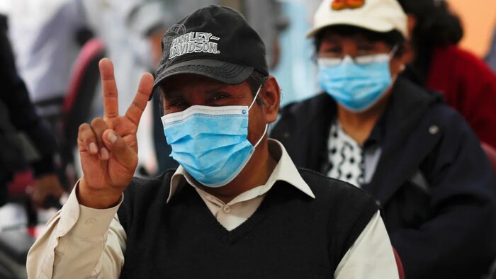 A man flashes a victory sign after getting a shot of the Sputnik V vaccine for COVID-19 at the start of vaccinations for people over age 60 at the Universidad Mayor de San Andres public university in La Paz, Bolivia, Tuesday, April 27, 2021.