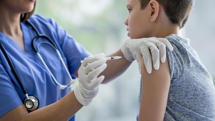 Un garçon d'environ 7 ans se fait vacciner par une infirmière.