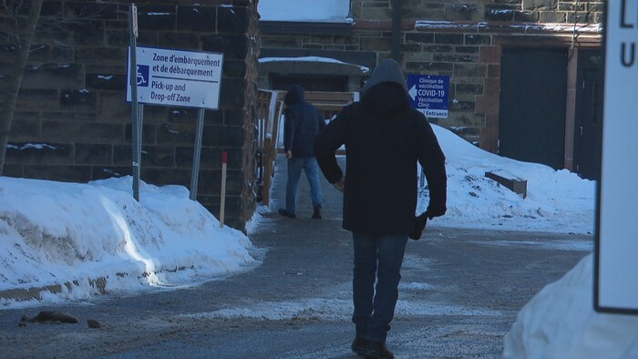 Deux personnes se dirigent vers l'entrée d'une clinique de vaccination.