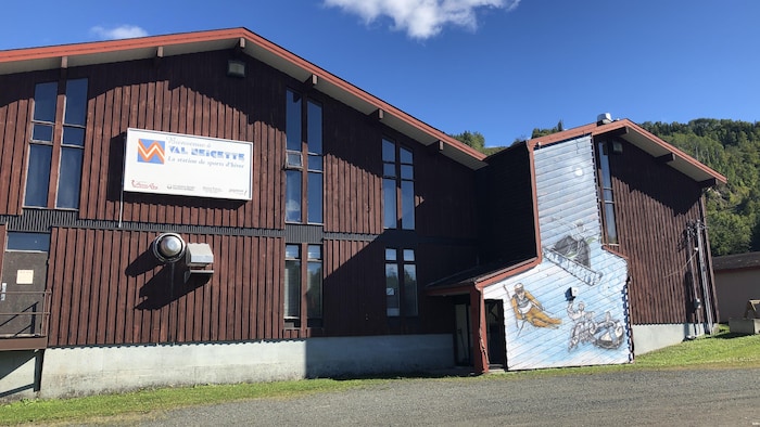 Un grand bâtiment en bois avec un panneau où il est inscrit Bienvenue à Val-Neigette.