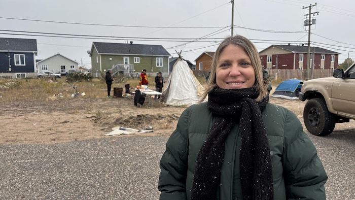 Valérie Santerre, portant un manteau d'hiver et un foulard autour du cou, sourit face à la caméra.