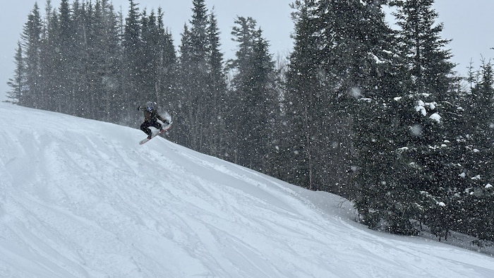Un planchiste fait un saut sur une piste de montagne de ski.