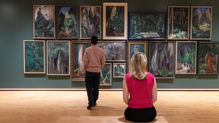 Deux personnes de dos faisant face aux oeuvres d'Emily Carr au musée.