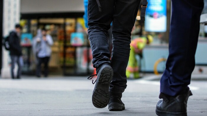Des passants dont on ne voit que les jambes marchent dans les rues de Vancouver.