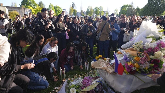 Des personnes s'attroupent autour de bouquets de fleurs à Vancouver, le 27 avril 2025.