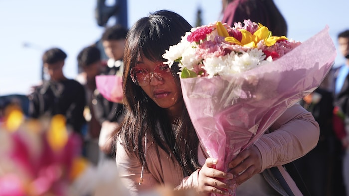 Une femme place des fleurs au sol, lors d'une vigile en hommage aux victimes du drame de Vancouver, le 27 avril 2025.