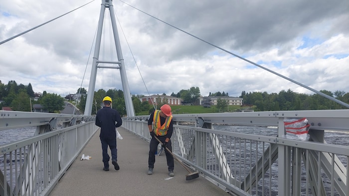 Deux hommes qui nettoient un pont.
