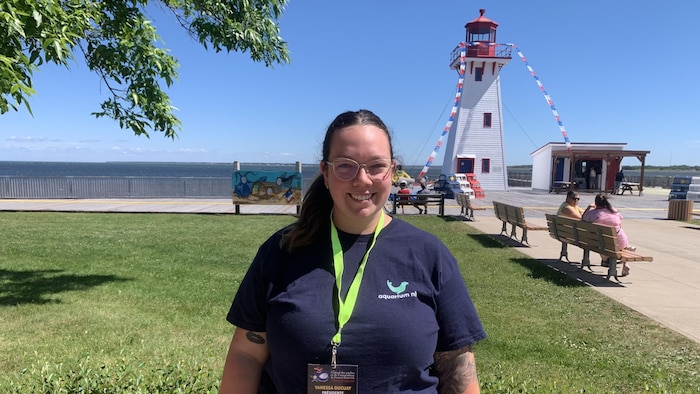 Une femme debout, dehors, devant un phare, à Shippagan.