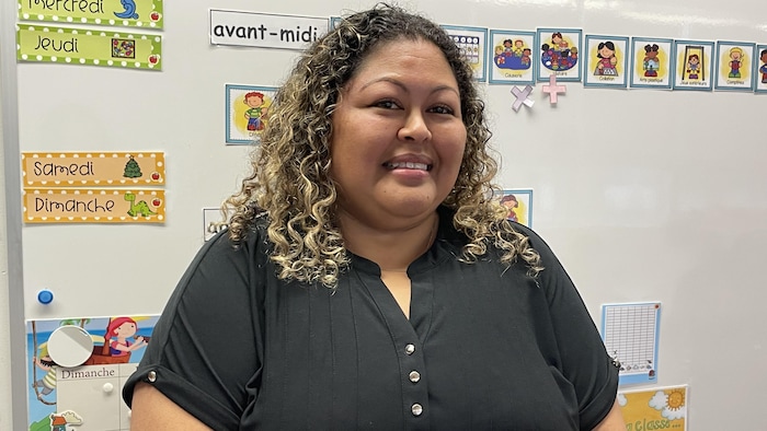 Vanessa Ibanez sourit en regardant la caméra; dernière elle, il y a des pictogrammes.