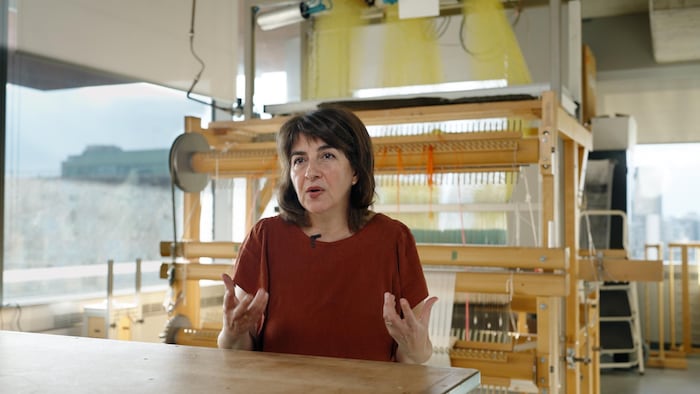 Une femme est assise devant un grand métier à tisser.