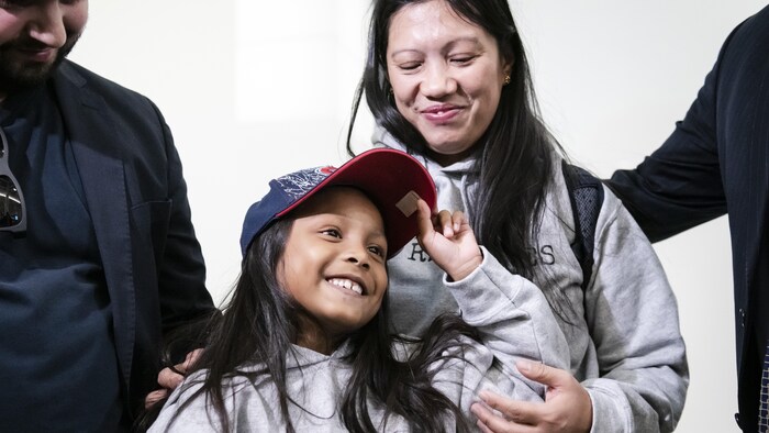 Vanessa Rodel et sa fille sourient. Elles portent un chandail de l'organisme qui les parraine, For the Refugees. Keana porte une casquette du Canadien de Montréal.