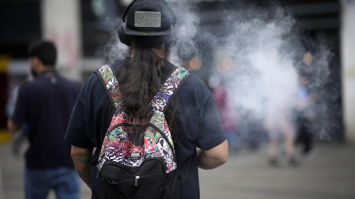 Un homme fume un dispositif de vapotage le 30 mai 2023 à Manchester, en Angleterre.