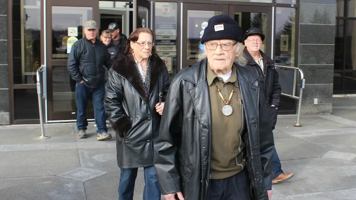 Jackie Vautour, un homme de 90 ans, sort du palais de justice. Quelques autres personnes en sortent aussi derrière lui.